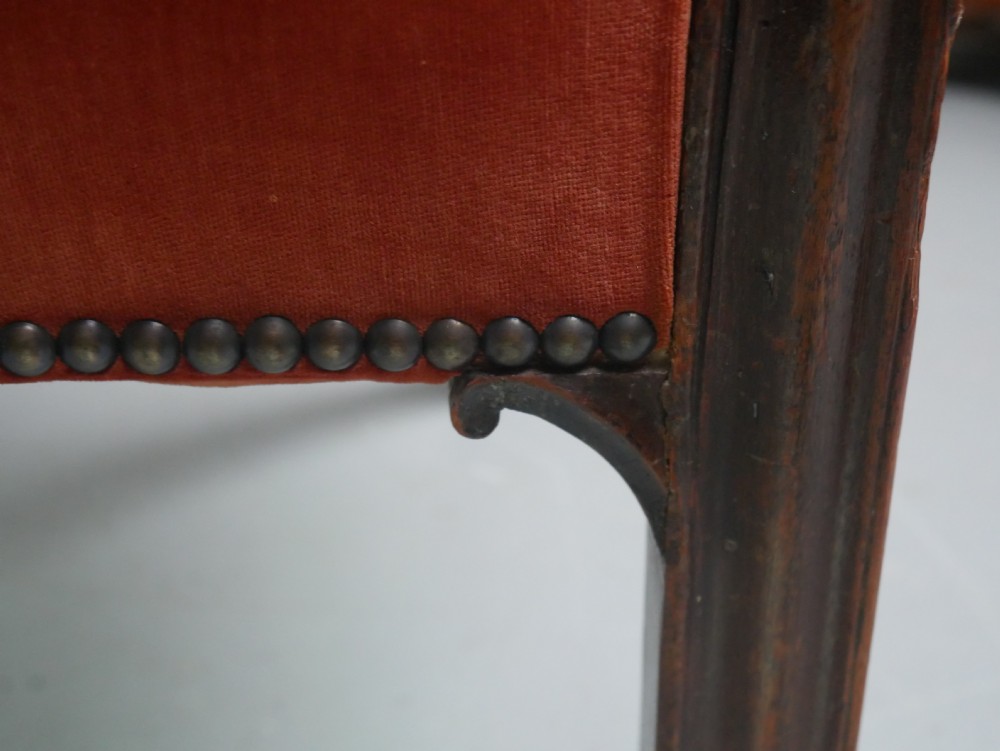 A Georgian high-backed barrel armchair upholstered in burnt orange velvet with brass stud trimming and dark mahogany legs. View VII