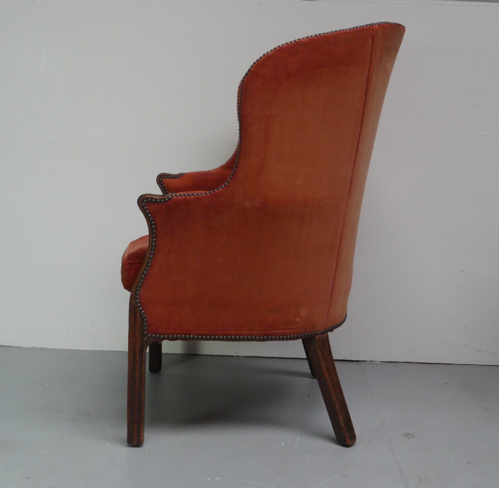 A Georgian high-backed barrel armchair upholstered in burnt orange velvet with brass stud trimming and dark mahogany legs. View VIII