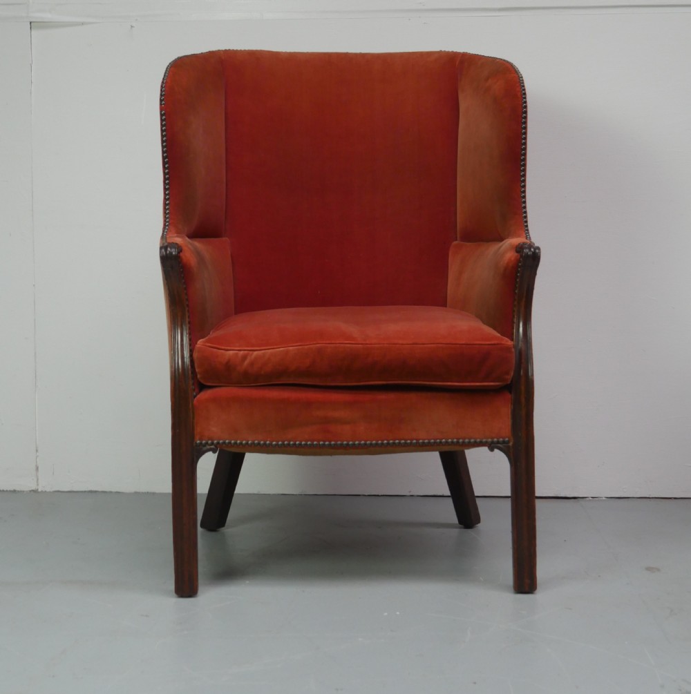 A Georgian high-backed barrel armchair upholstered in burnt orange velvet with brass stud trimming and dark mahogany legs. View IX