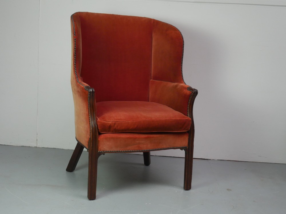 A Georgian high-backed barrel armchair upholstered in burnt orange velvet with brass stud trimming and dark mahogany legs. View X