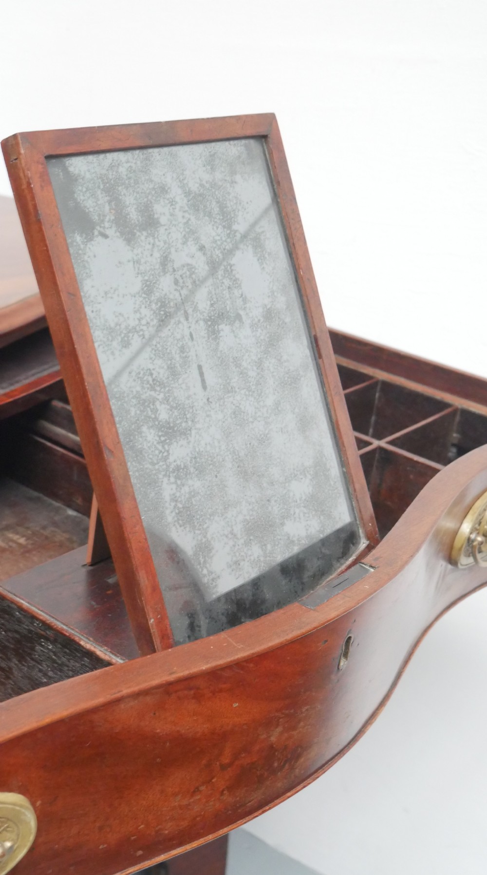 A Georgian mahogany chest of drawers featuring a wave-like serpentine front, four graduated drawers with oval brass handles, and bracket feet. View XI