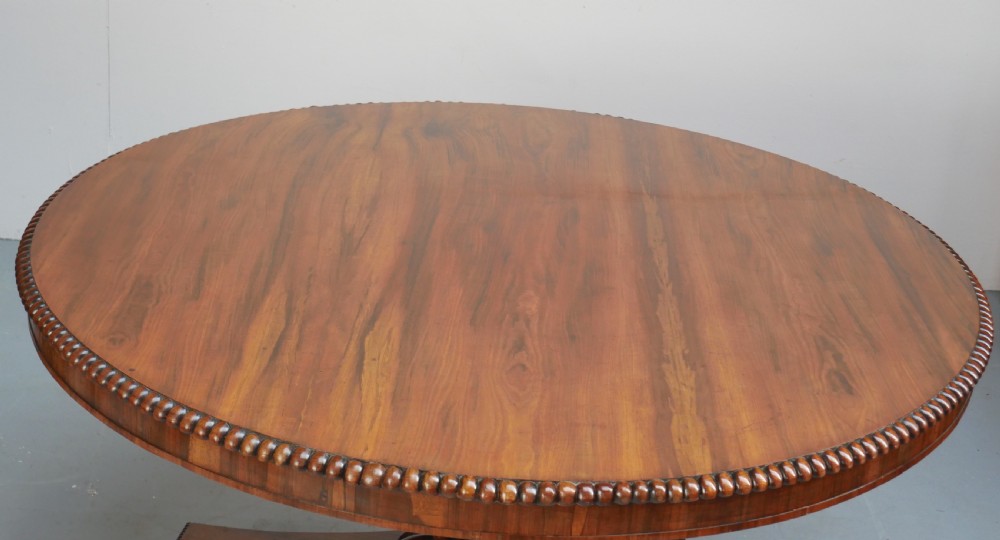 A Regency mahogany circular centre table featuring a beaded moulding edge, a carved gadrooned pedestal, and a triform base with scrolled feet. View IV