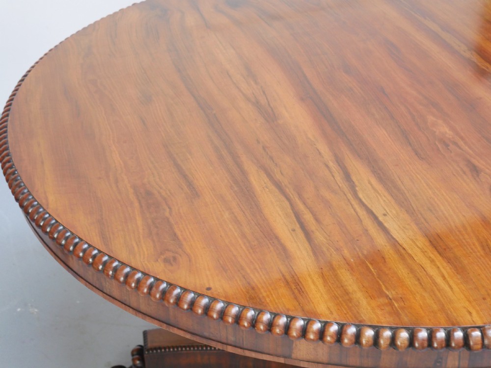 A Regency mahogany circular centre table featuring a beaded moulding edge, a carved gadrooned pedestal, and a triform base with scrolled feet. View VII
