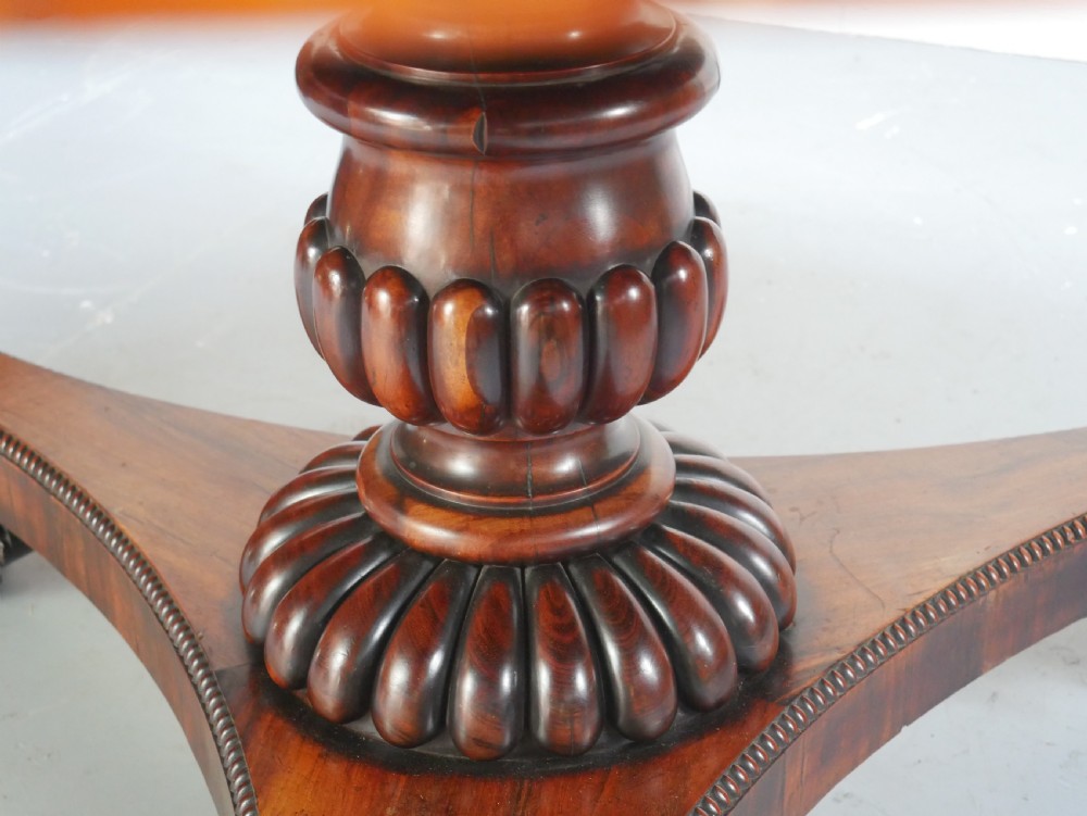 A Regency mahogany circular centre table featuring a beaded moulding edge, a carved gadrooned pedestal, and a triform base with scrolled feet. View VIII
