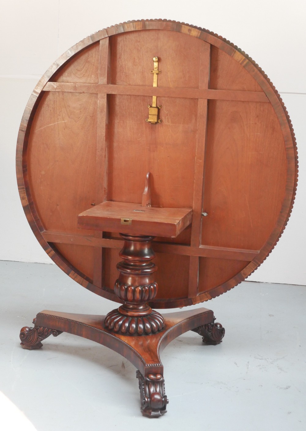 A Regency mahogany circular centre table featuring a beaded moulding edge, a carved gadrooned pedestal, and a triform base with scrolled feet. View XI