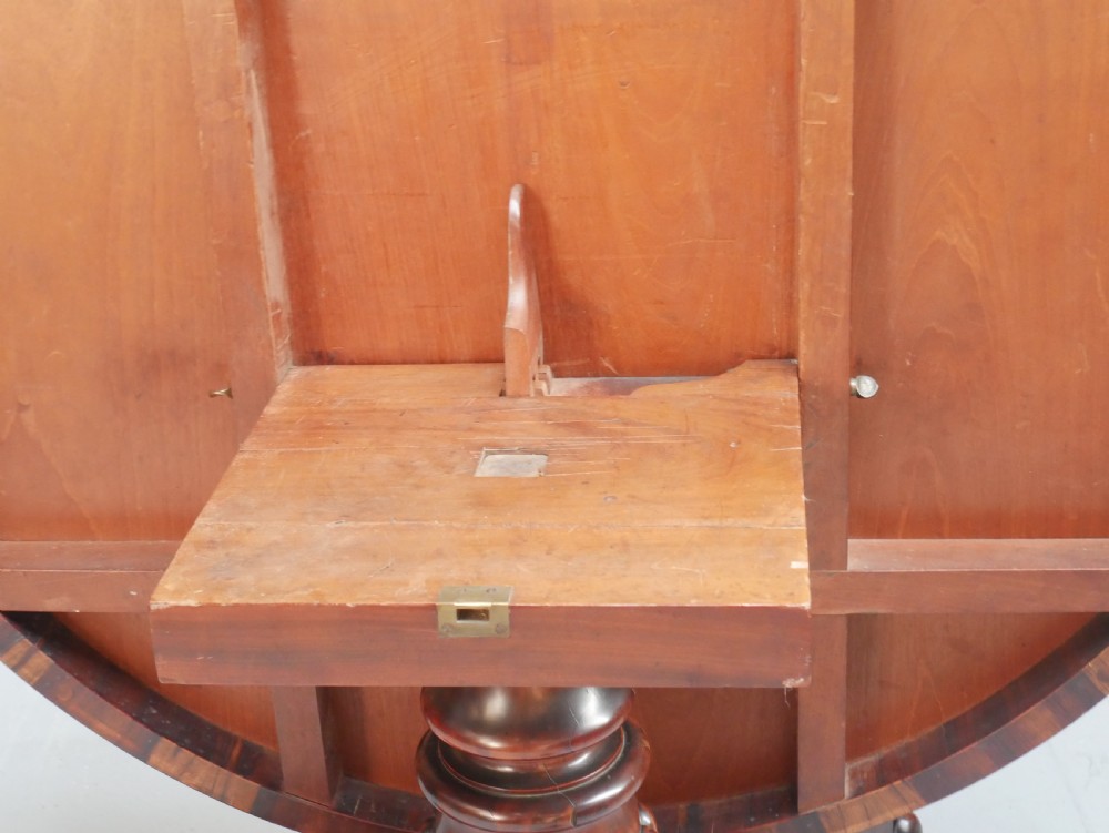 A Regency mahogany circular centre table featuring a beaded moulding edge, a carved gadrooned pedestal, and a triform base with scrolled feet. View XII