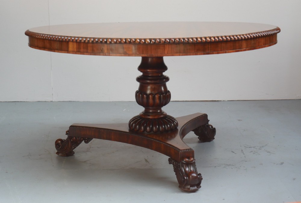 A Regency mahogany circular centre table featuring a beaded moulding edge, a carved gadrooned pedestal, and a triform base with scrolled feet. View XIV