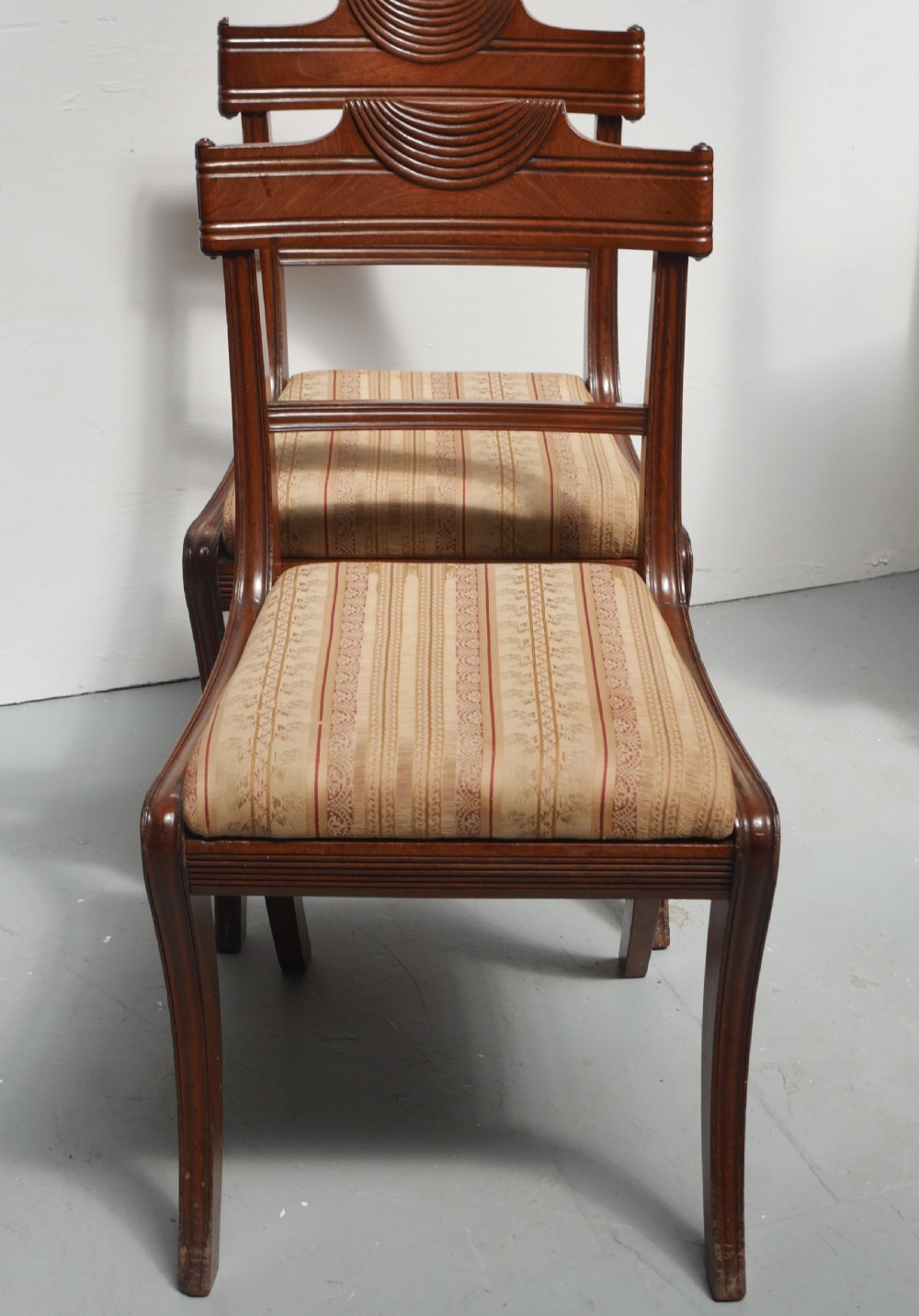 Set of four Regency mahogany dining chairs featuring carved crest rails, horizontal crossbars, and padded seats. View II