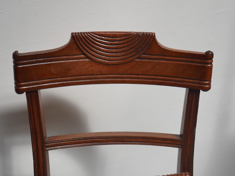 Set of four Regency mahogany dining chairs featuring carved crest rails, horizontal crossbars, and padded seats. View V