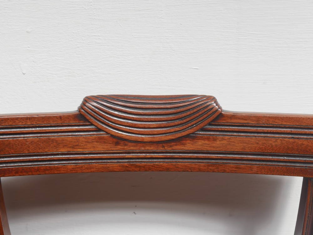 Set of four Regency mahogany dining chairs featuring carved crest rails, horizontal crossbars, and padded seats. View VI
