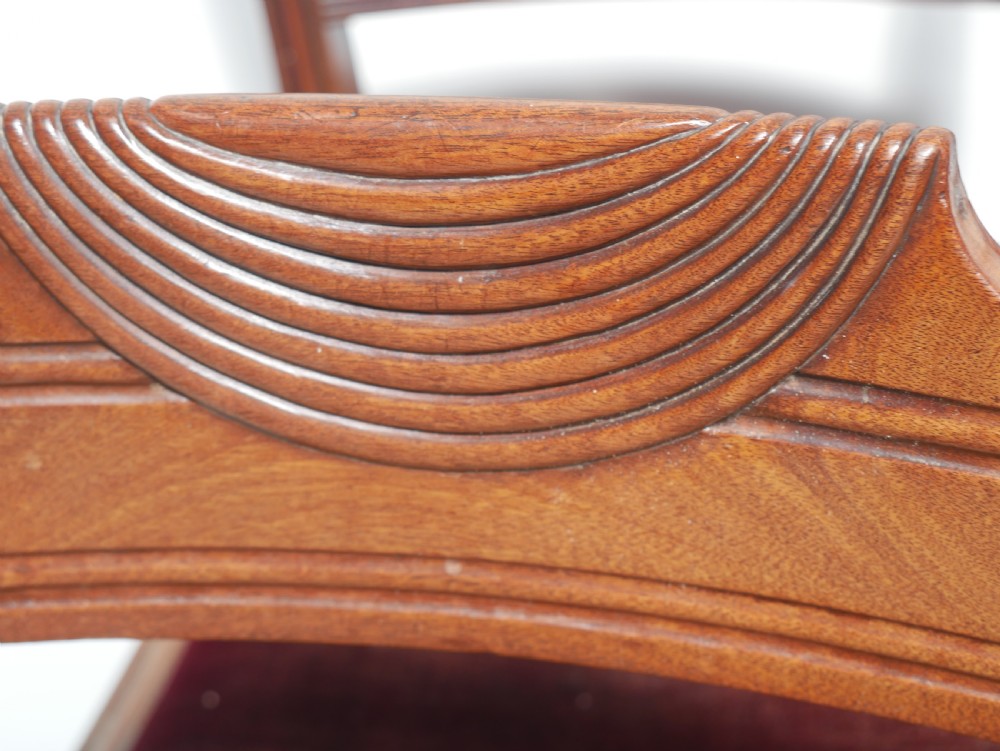 Set of four Regency mahogany dining chairs featuring carved crest rails, horizontal crossbars, and padded seats. View VII