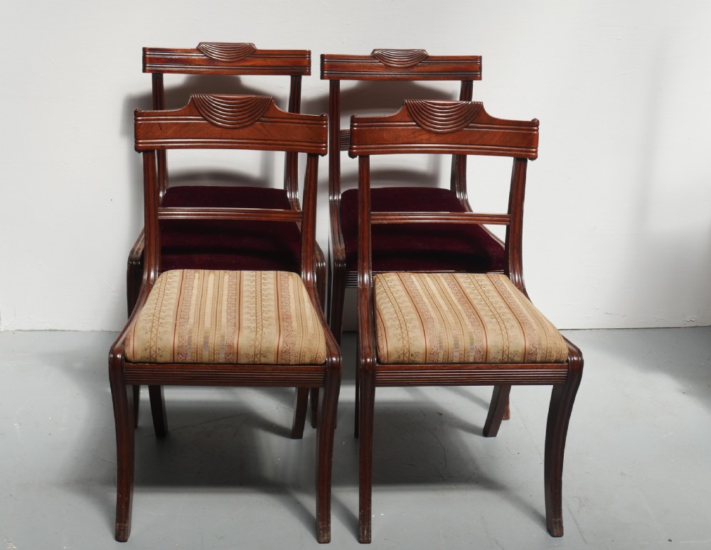 Set of four Regency mahogany dining chairs featuring carved crest rails, horizontal crossbars, and padded seats. View X