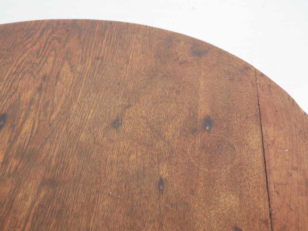 A dark Georgian oak cricket table featuring a circular plank top, three tapered legs, and a lower triangular shelf. View III