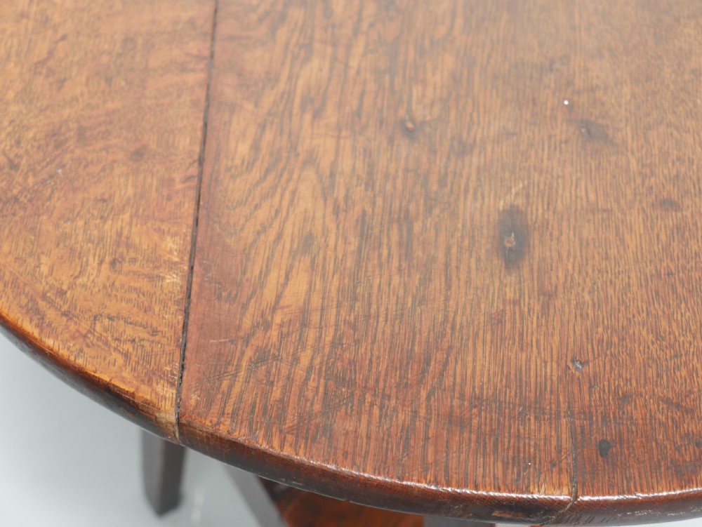 A dark Georgian oak cricket table featuring a circular plank top, three tapered legs, and a lower triangular shelf. View IV
