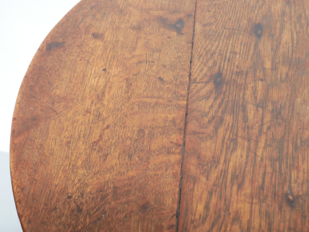 A dark Georgian oak cricket table featuring a circular plank top, three tapered legs, and a lower triangular shelf. View V