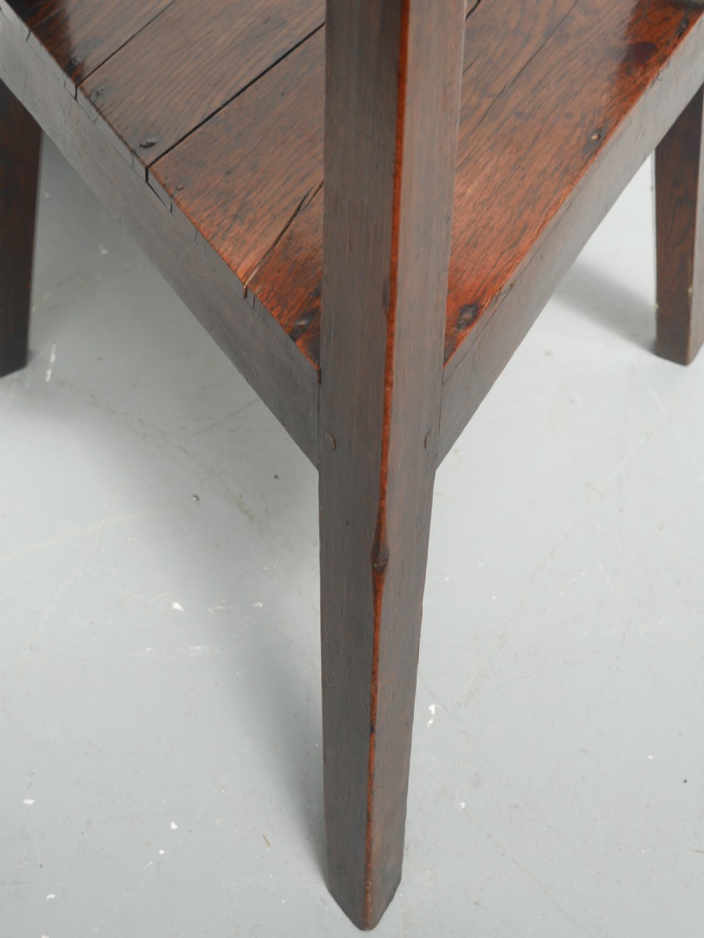 A dark Georgian oak cricket table featuring a circular plank top, three tapered legs, and a lower triangular shelf. View VI
