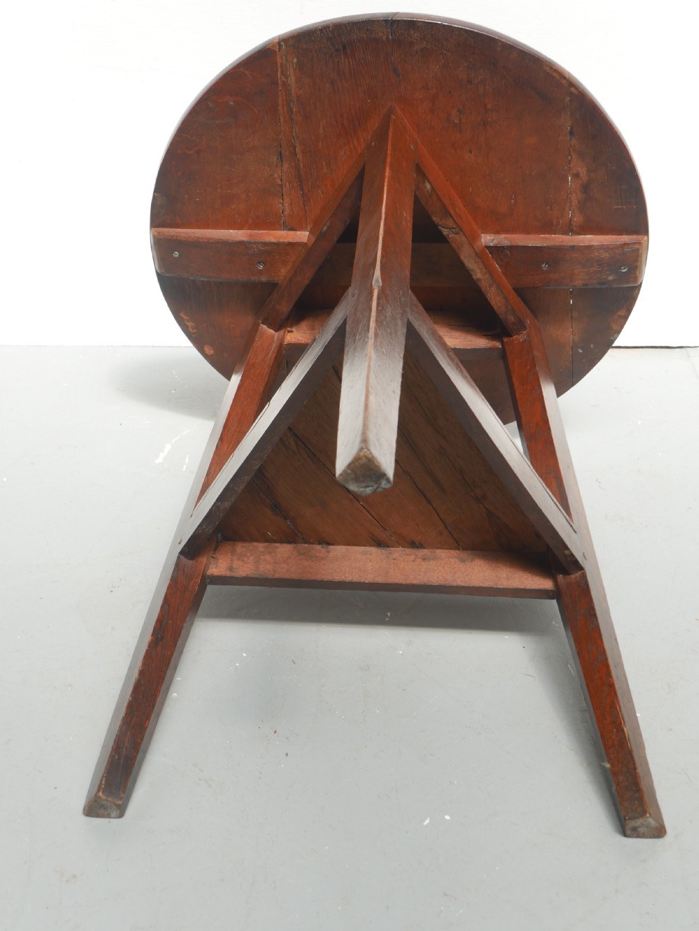 A dark Georgian oak cricket table featuring a circular plank top, three tapered legs, and a lower triangular shelf. View X