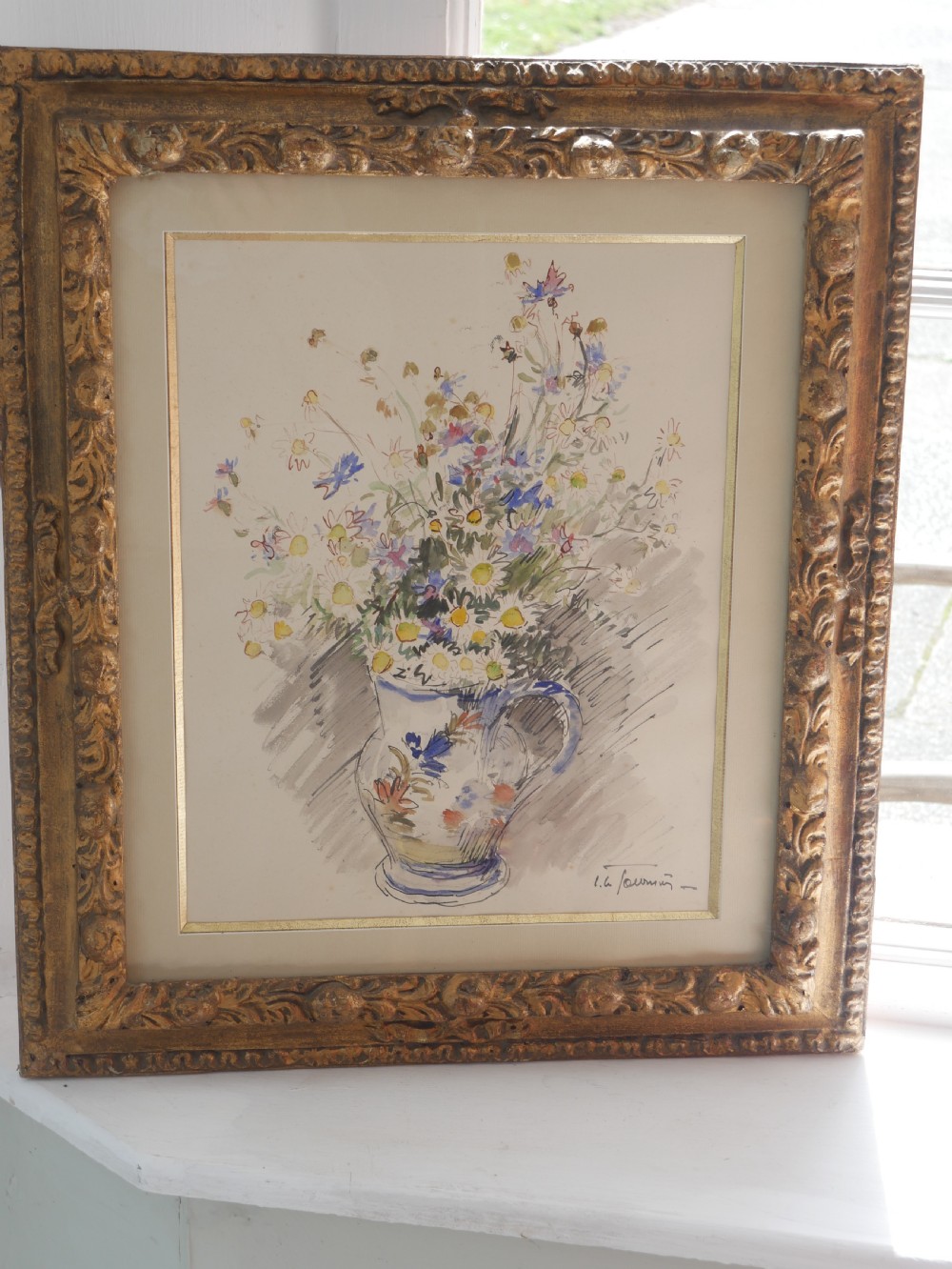 A framed floral watercolour still life painting depicting a bouquet of summer wildflowers in a ceramic jug within a carved giltwood frame. View II
