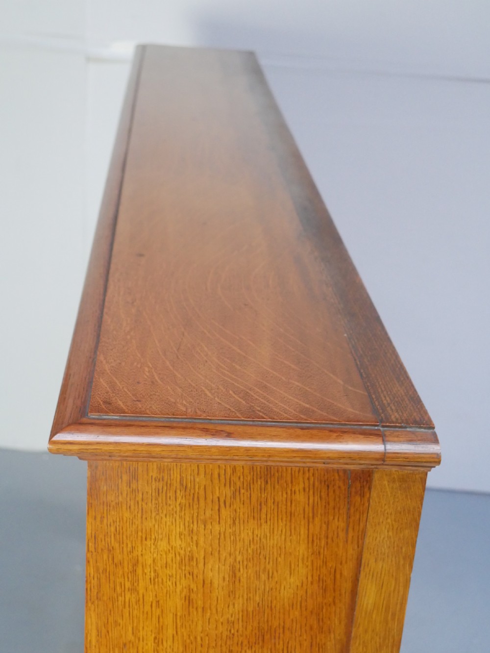A large double-bay open oak bookcase with horizontal shelves filled with antique leather-bound books. View II