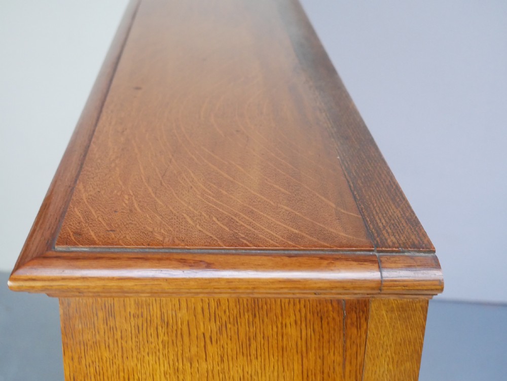 A large double-bay open oak bookcase with horizontal shelves filled with antique leather-bound books. View III