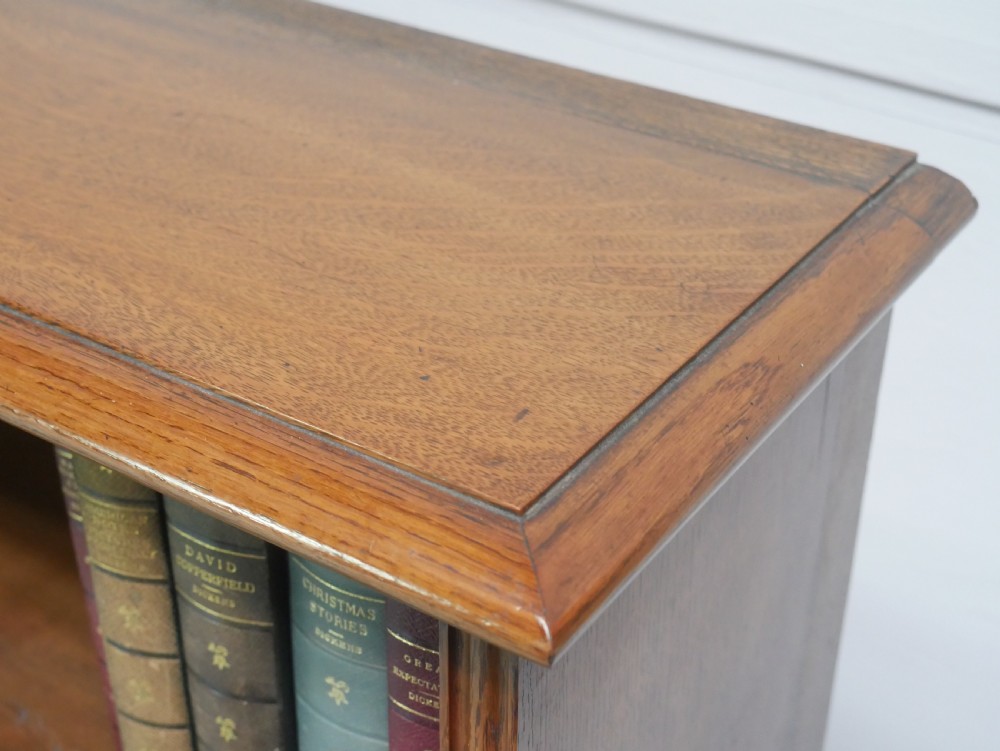 A large double-bay open oak bookcase with horizontal shelves filled with antique leather-bound books. View IV