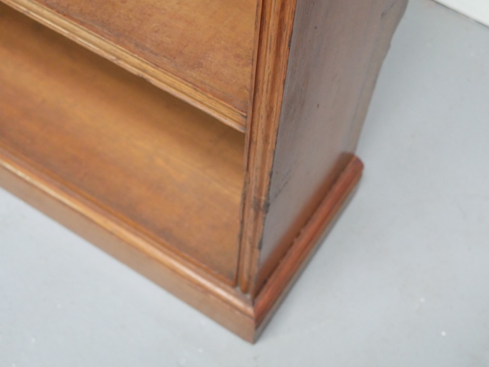 A large double-bay open oak bookcase with horizontal shelves filled with antique leather-bound books. View V