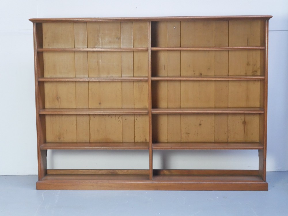 A large double-bay open oak bookcase with horizontal shelves filled with antique leather-bound books. View VI