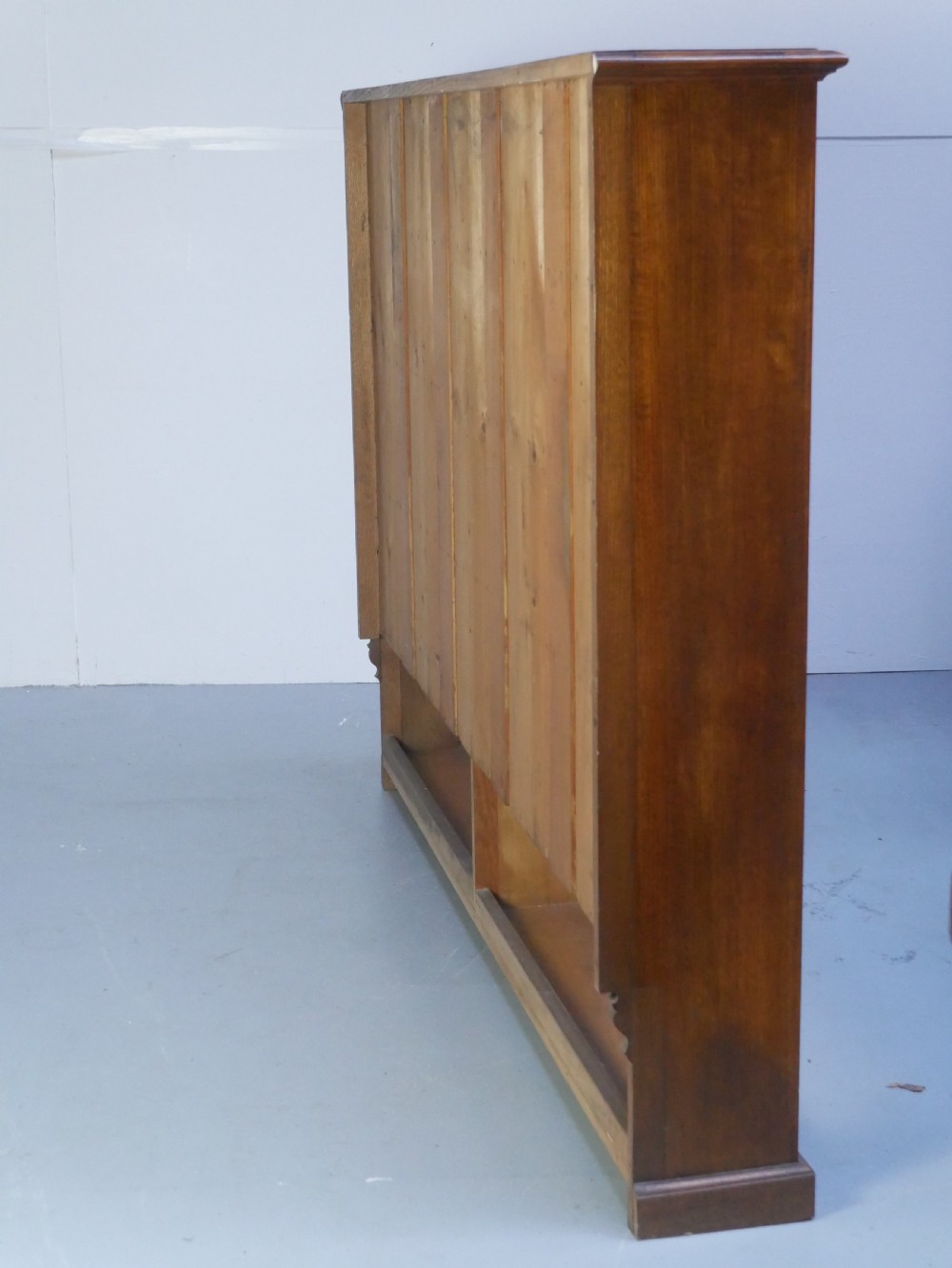 A large double-bay open oak bookcase with horizontal shelves filled with antique leather-bound books. View X