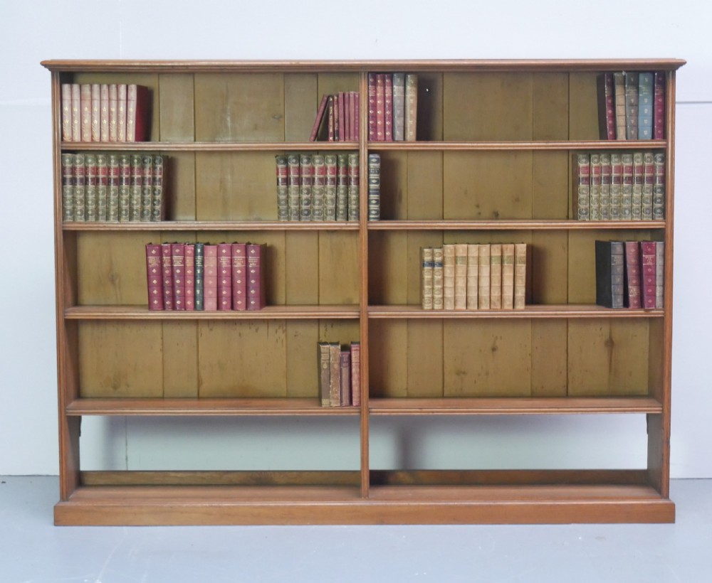 A large double-bay open oak bookcase with horizontal shelves filled with antique leather-bound books. View XI