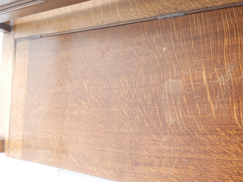 A medium brown oak hall bench featuring a tri-panel backrest, turned armrest supports, and a hinged lid chest base. View IX