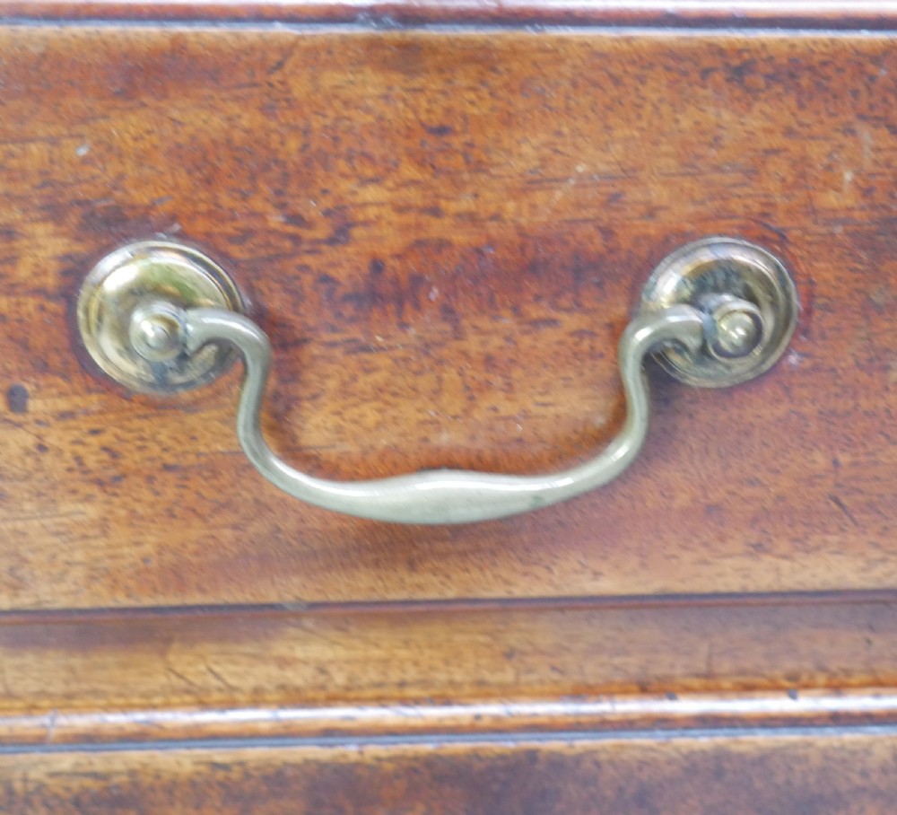A Georgian mahogany small chest of drawers featuring four graduated drawers, brass swan-neck drop handles, keyhole escutcheons, and shaped bracket feet. View IV