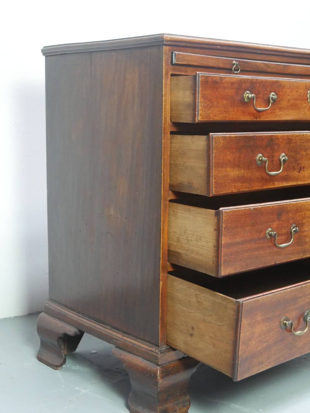 A Georgian mahogany small chest of drawers featuring four graduated drawers, brass swan-neck drop handles, keyhole escutcheons, and shaped bracket feet. View V