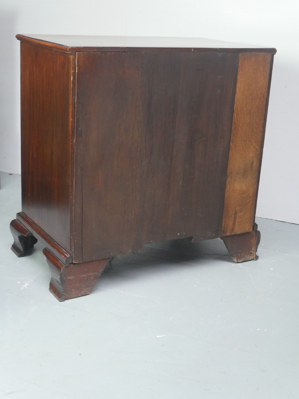 A Georgian mahogany small chest of drawers featuring four graduated drawers, brass swan-neck drop handles, keyhole escutcheons, and shaped bracket feet. View VII
