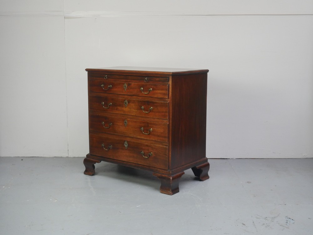 A Georgian mahogany small chest of drawers featuring four graduated drawers, brass swan-neck drop handles, keyhole escutcheons, and shaped bracket feet. View X