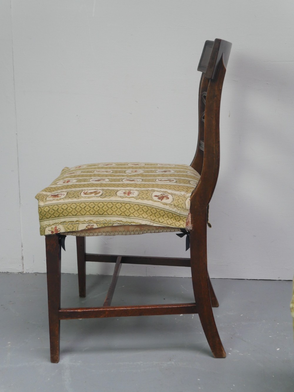 A set of four Scottish Georgian mahogany dining chairs featuring carved bow splats, square legs with stretchers, and green and cream patterned upholstery. View IV