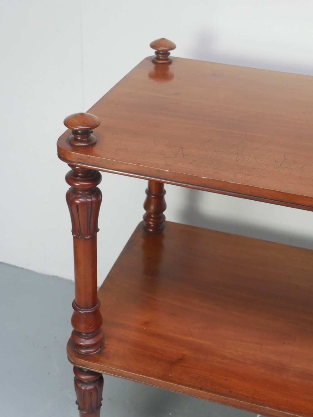 A 19th-century mahogany two-tier buffet table featuring turned support columns, corner finials, and brass castors. View IV
