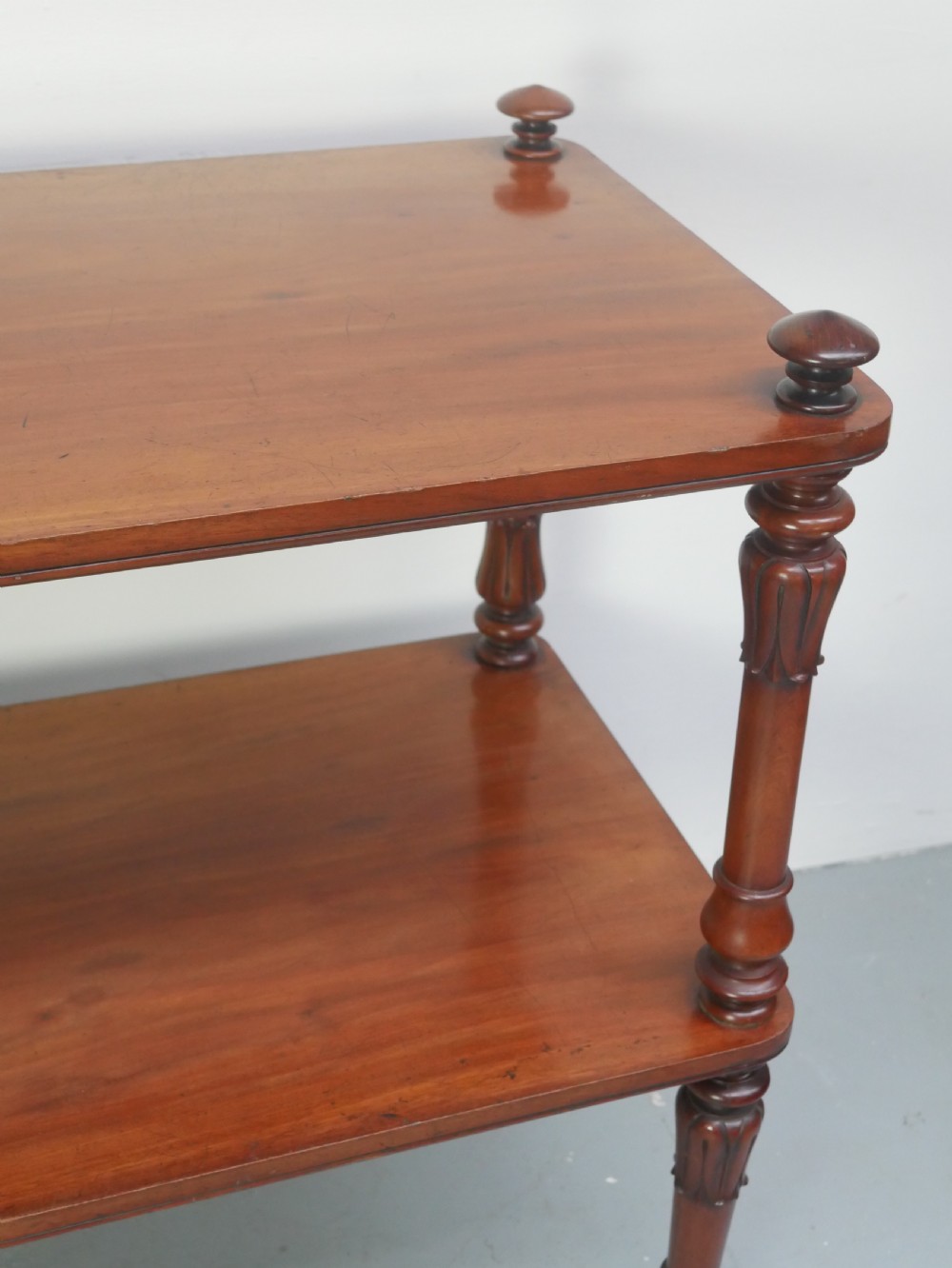A 19th-century mahogany two-tier buffet table featuring turned support columns, corner finials, and brass castors. View V