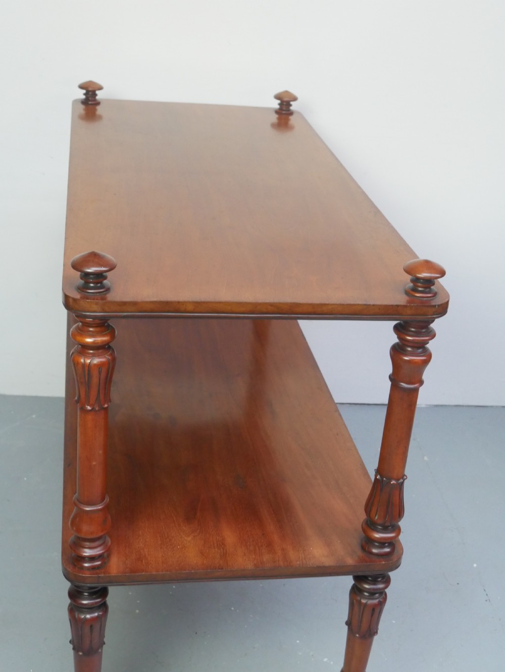 A 19th-century mahogany two-tier buffet table featuring turned support columns, corner finials, and brass castors. View VII