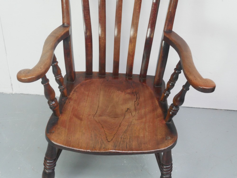A dark brown wooden country armchair featuring a high spindle back, curved crest rail, shaped seat, and turned legs. View II