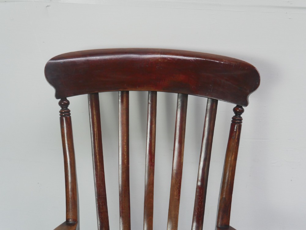 A dark brown wooden country armchair featuring a high spindle back, curved crest rail, shaped seat, and turned legs. View III