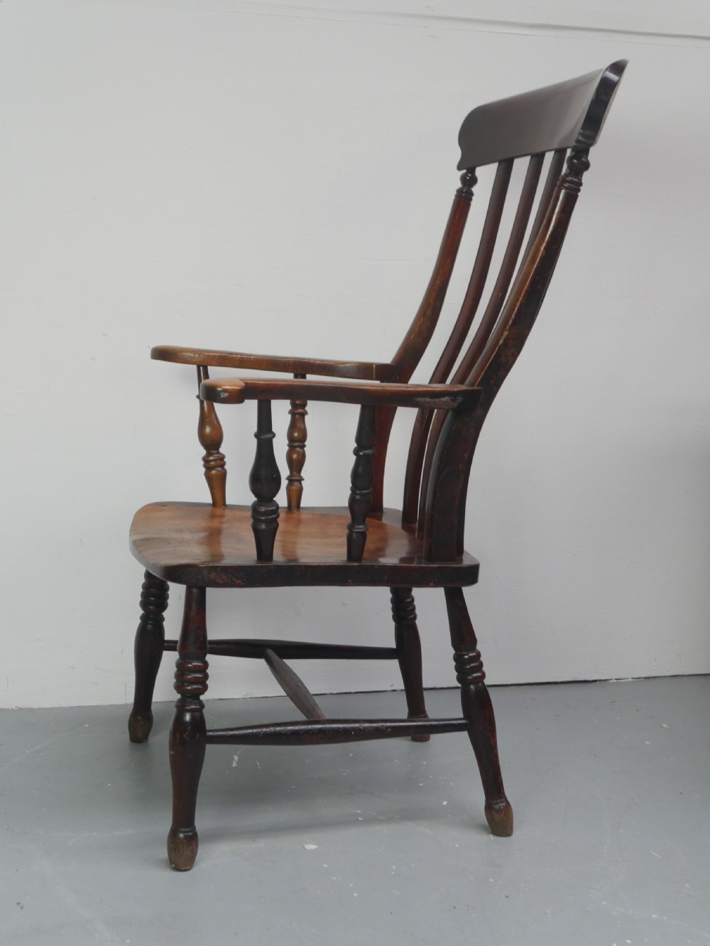 A dark brown wooden country armchair featuring a high spindle back, curved crest rail, shaped seat, and turned legs. View IV