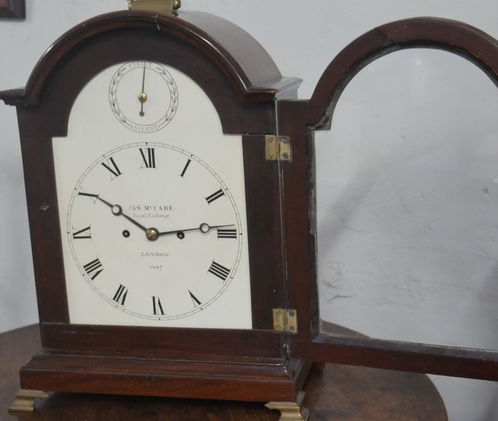 A Georgian mahogany bracket clock featuring an arched top with a brass handle, white dial with Roman numerals, and strike silent sub-dial. View II