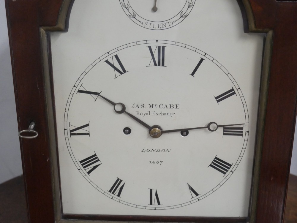 A Georgian mahogany bracket clock featuring an arched top with a brass handle, white dial with Roman numerals, and strike silent sub-dial. View VI