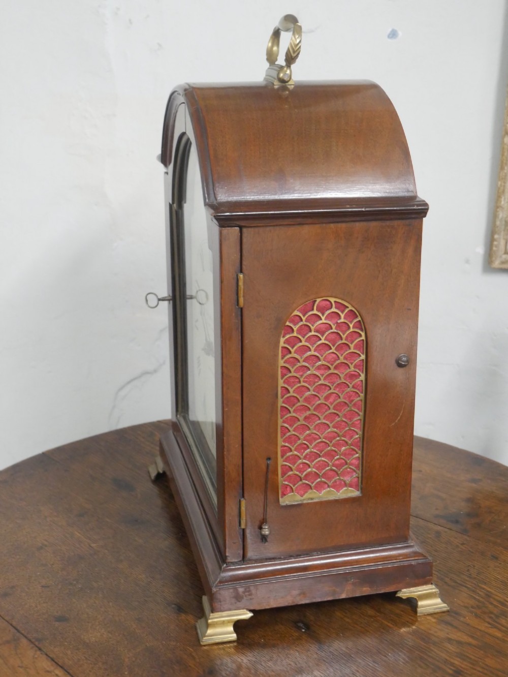 A Georgian mahogany bracket clock featuring an arched top with a brass handle, white dial with Roman numerals, and strike silent sub-dial. View X