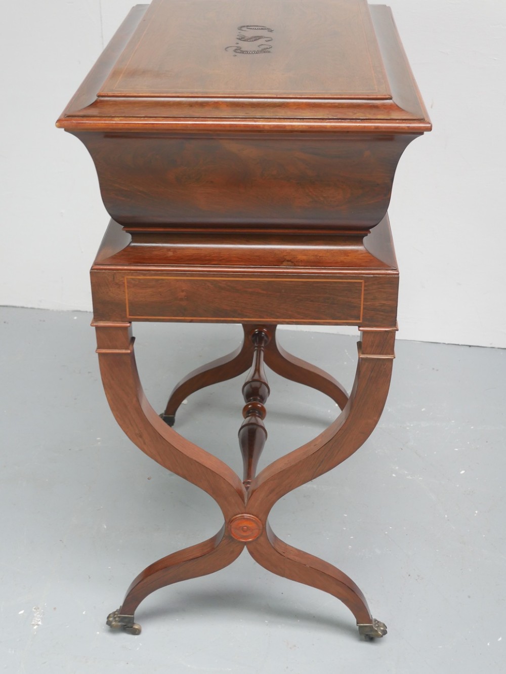 An antique French rosewood box with inlaid monogram resting on a matching stand with curved legs and brass castors. View VI