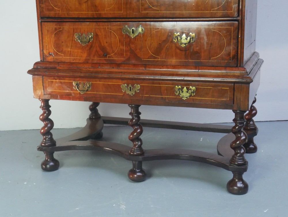 A late 17th-century William and Mary walnut chest on stand featuring multiple drawers with feather inlay, barley twist legs, and bun feet. View II