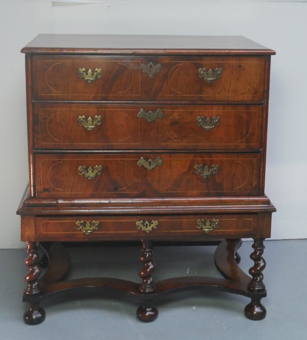 A late 17th-century William and Mary walnut chest on stand featuring multiple drawers with feather inlay, barley twist legs, and bun feet. View XIV