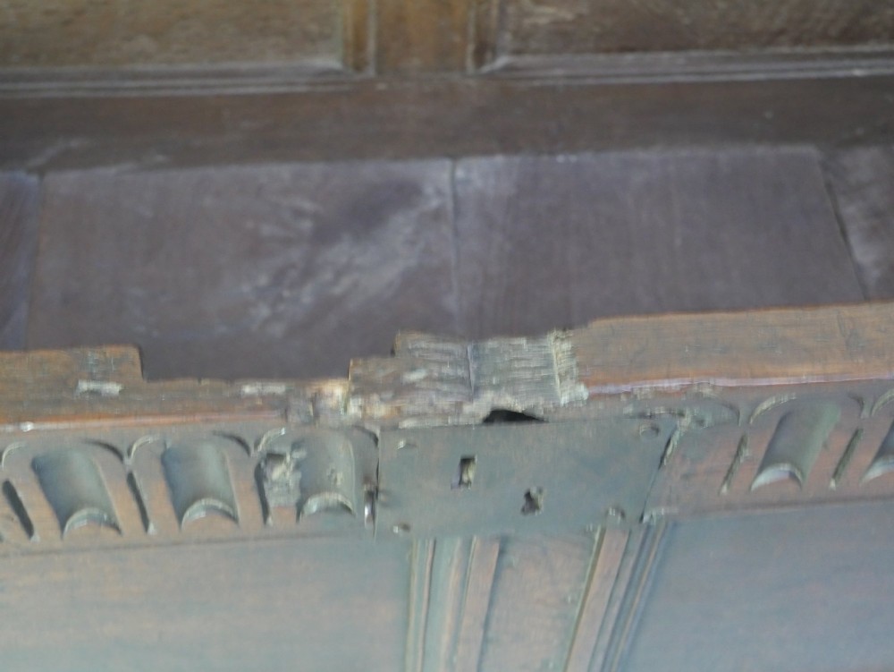 A dark brown oak coffer featuring a carved fluted frieze, double front panels, and a hinged lid with carved geometric border details. View IV