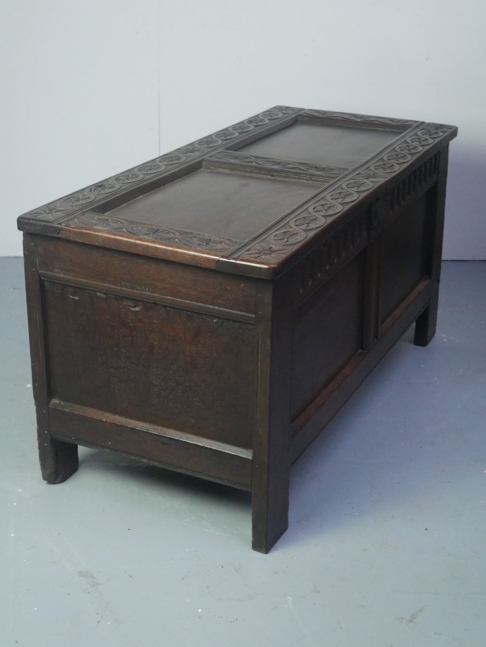 A dark brown oak coffer featuring a carved fluted frieze, double front panels, and a hinged lid with carved geometric border details. View VIII