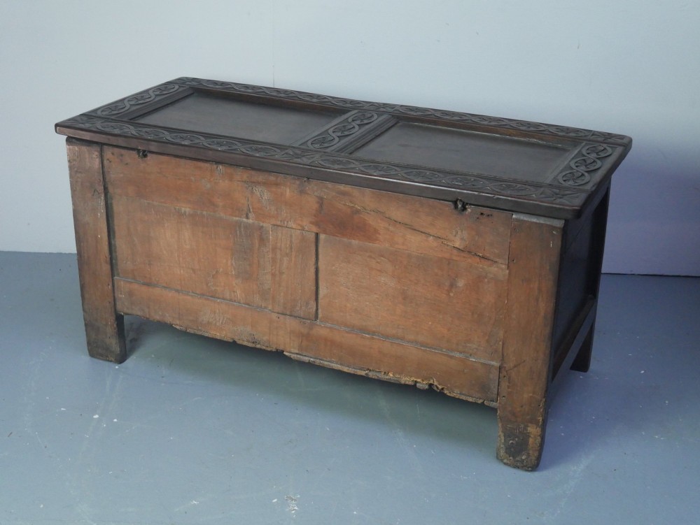 A dark brown oak coffer featuring a carved fluted frieze, double front panels, and a hinged lid with carved geometric border details. View IX